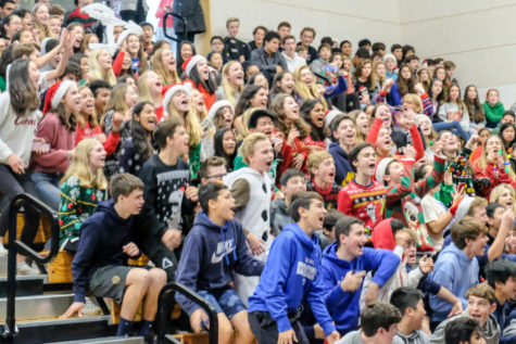 Students cheer in the gym bleachers during the 2019 holiday assembly. The annual holiday assembly always includes both the middle school and high school, but more assemblies should be held to further connect these two groups. Photo courtesy of Pete Zivkov.