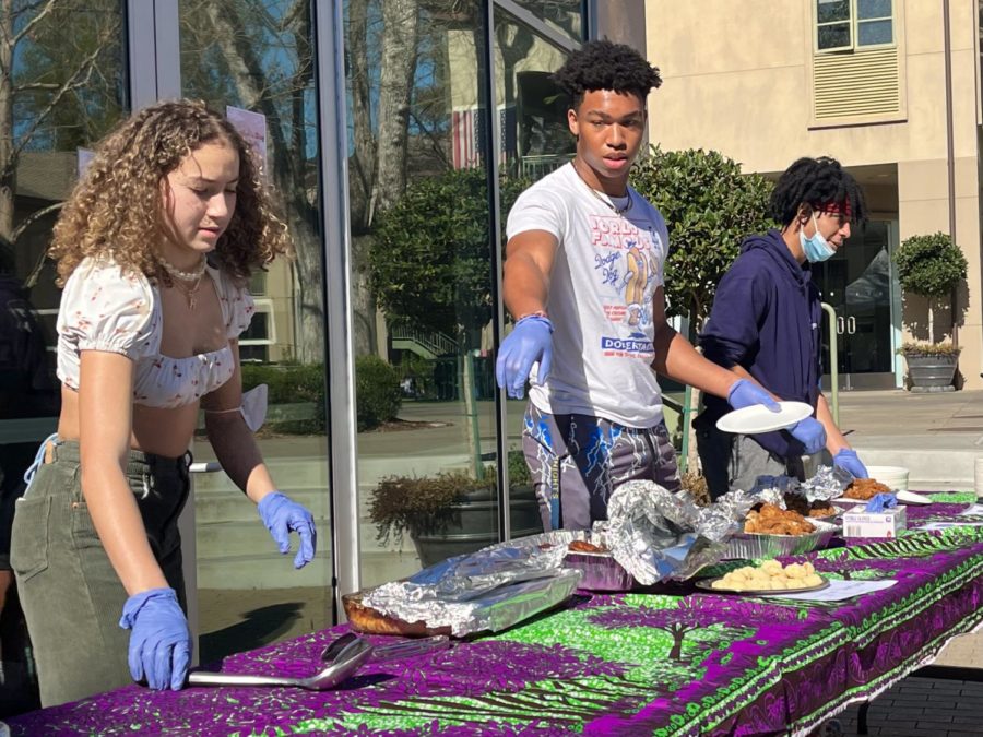 Senior Sammie Floyd, junior Ralston Raphael and sophomore Willis Johnson serve traditional African American foods at a lunchtime barbecue fundraiser outside the Student Center on Friday, Feb. 11. Staff photo: Karen Xin.