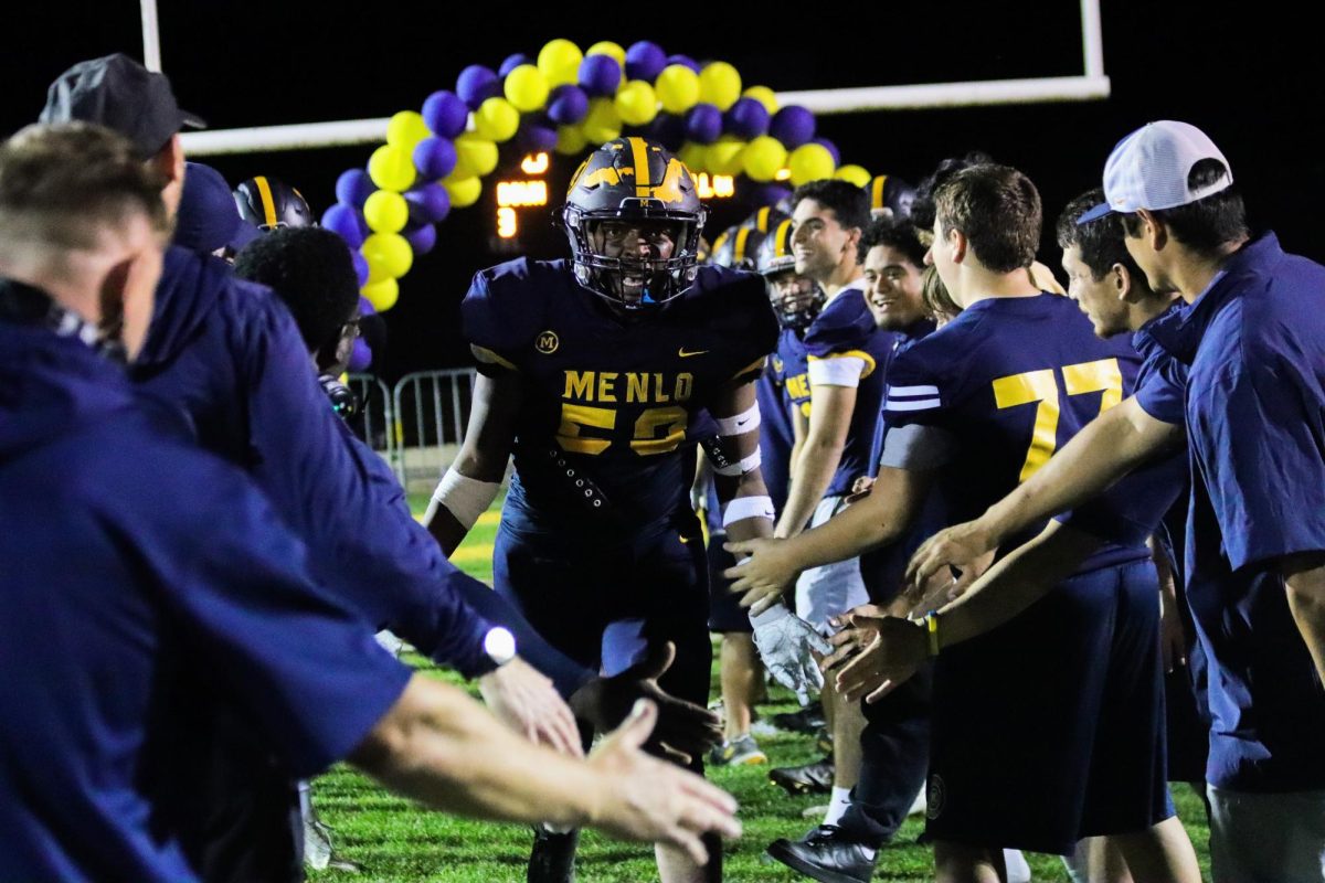 During player introductions, senior lineman Parker Ashton runs through the tunnel created by his teammates and coaches. Staff photo: Asher Darling