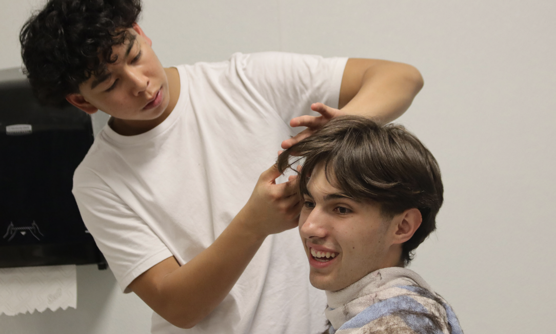 Sophomore Evan Arcilla gives senior Sam Reznik a haircut. Staff photo: Asher Darling
