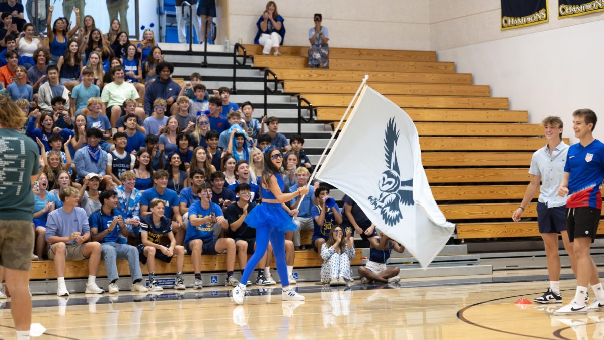 Spirit Ambassador, Lapolla member and senior Scarlett Bundy waves the blue Lapolla flag during the first competition between the houses on Sept. 6, 2024. Photo courtesy of Menlo Flickr.