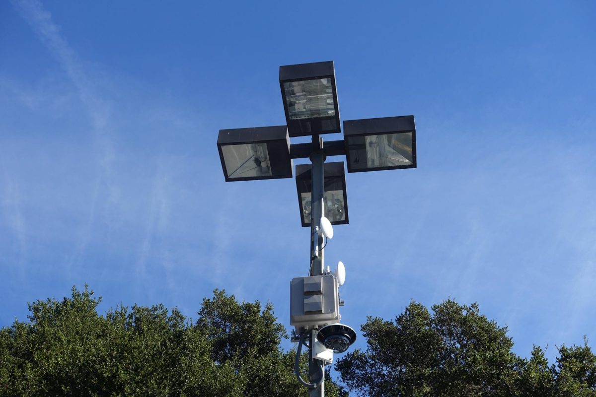 A recently-installed camera is attached to a light in the student parking lot.