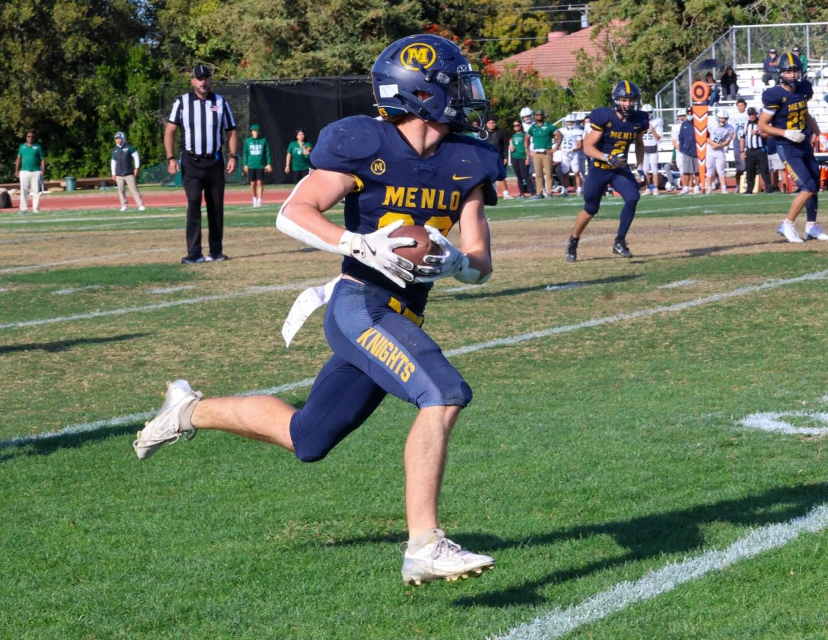 Junior Chuck Wynn runs with the ball after receiving a pass from junior quarterback Jack Freehill, gaining yardage that led to the Knights’ first touchdown.