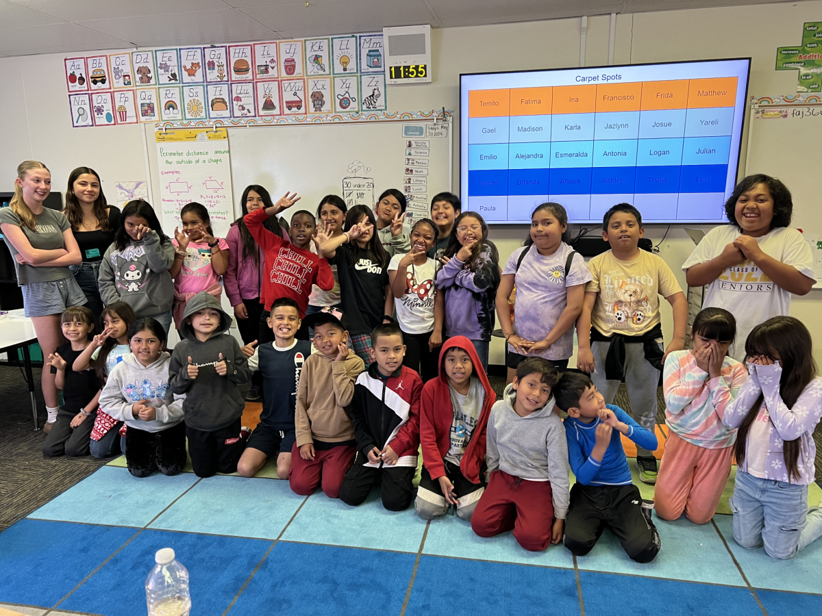 Seniors Veronica Taira and Annika Talwar pose with the students they tutor at Belle Haven Elementary School. Photo courtesy of Talwar