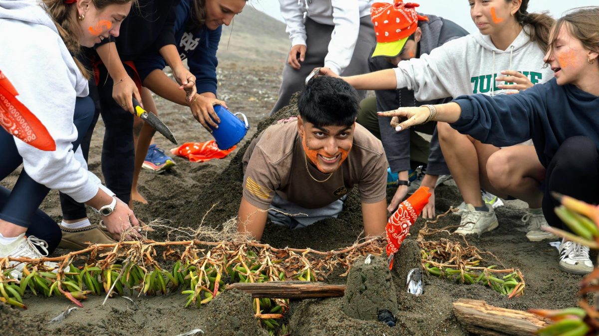 Senior Sachin Sandhu smiles as the rest of his advocacy buries him during a sandcastle building competition. 